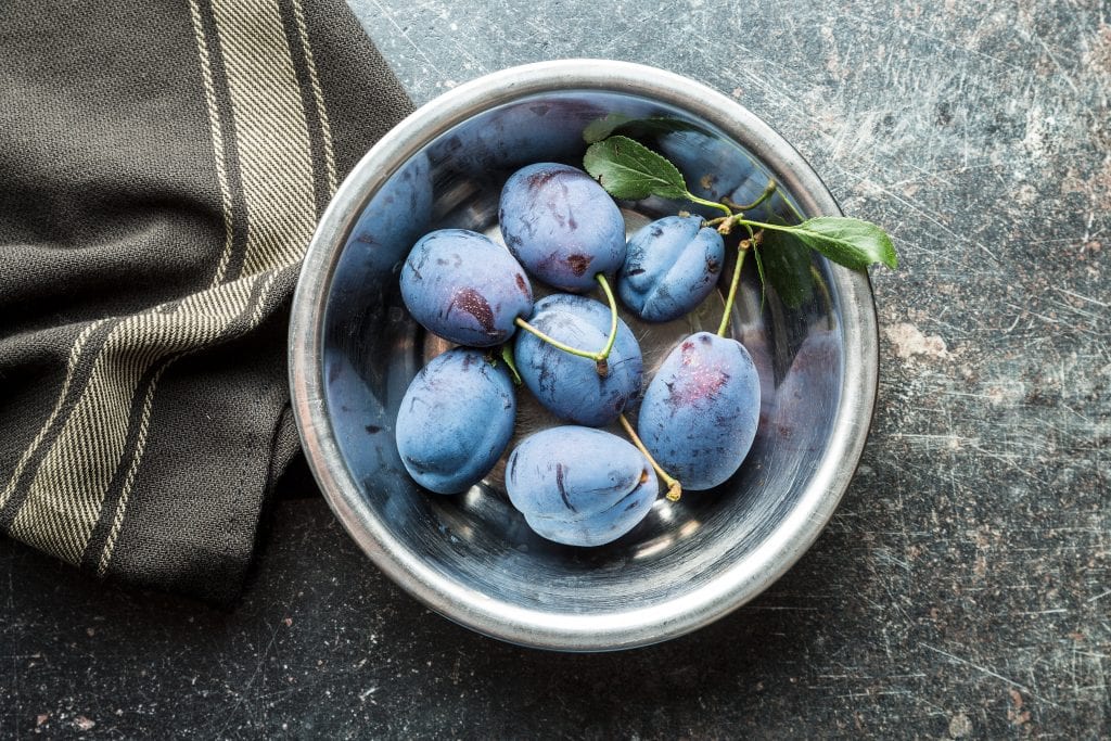 Fresh blue plums in bowl. Top view.